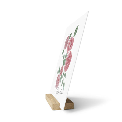 Card with pink roses on a white background, standing on a wooden stand.