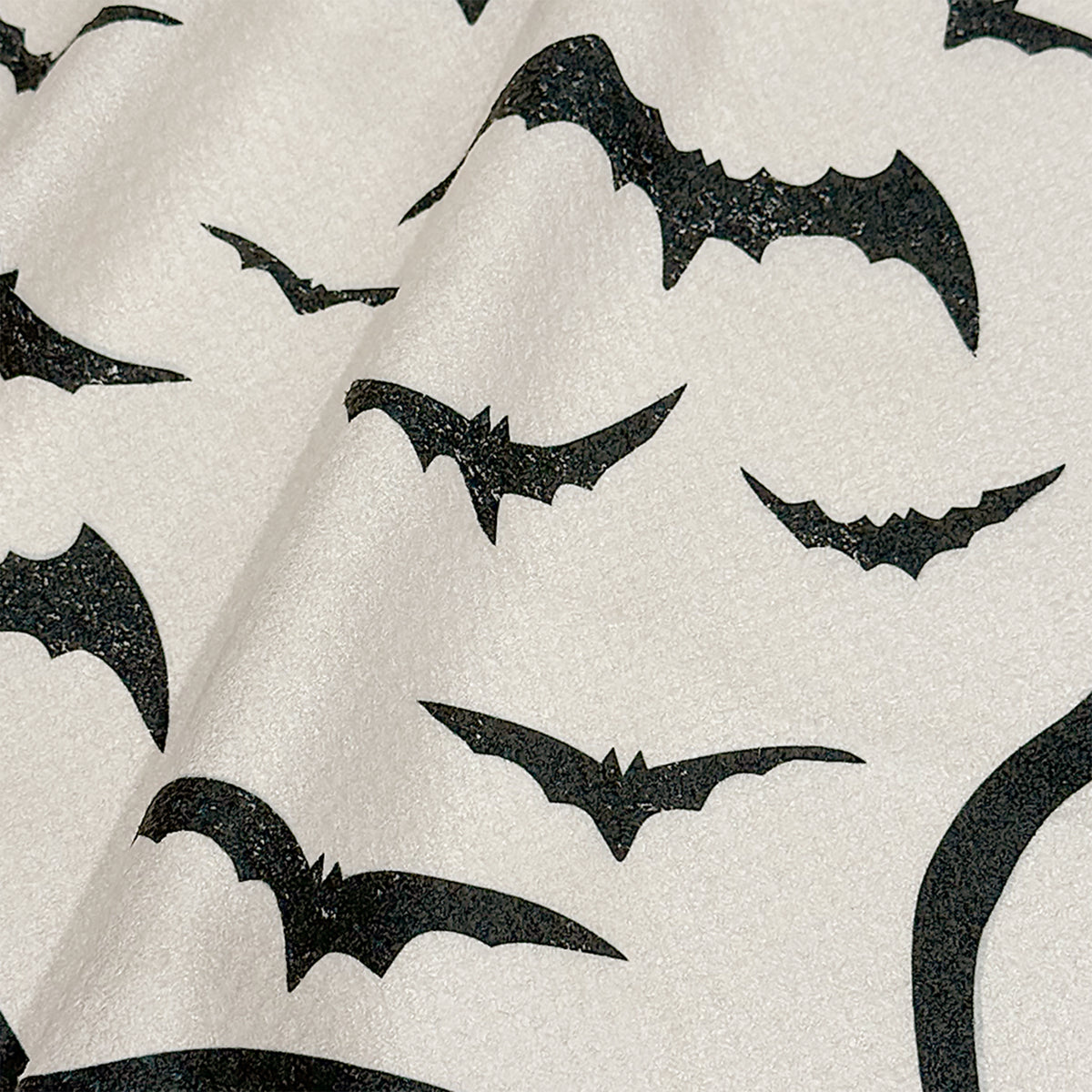Close up detail of Bat Bash Halloween tea towel showing inky black bats in flight on cream background, 723 & Co. Design Studio
