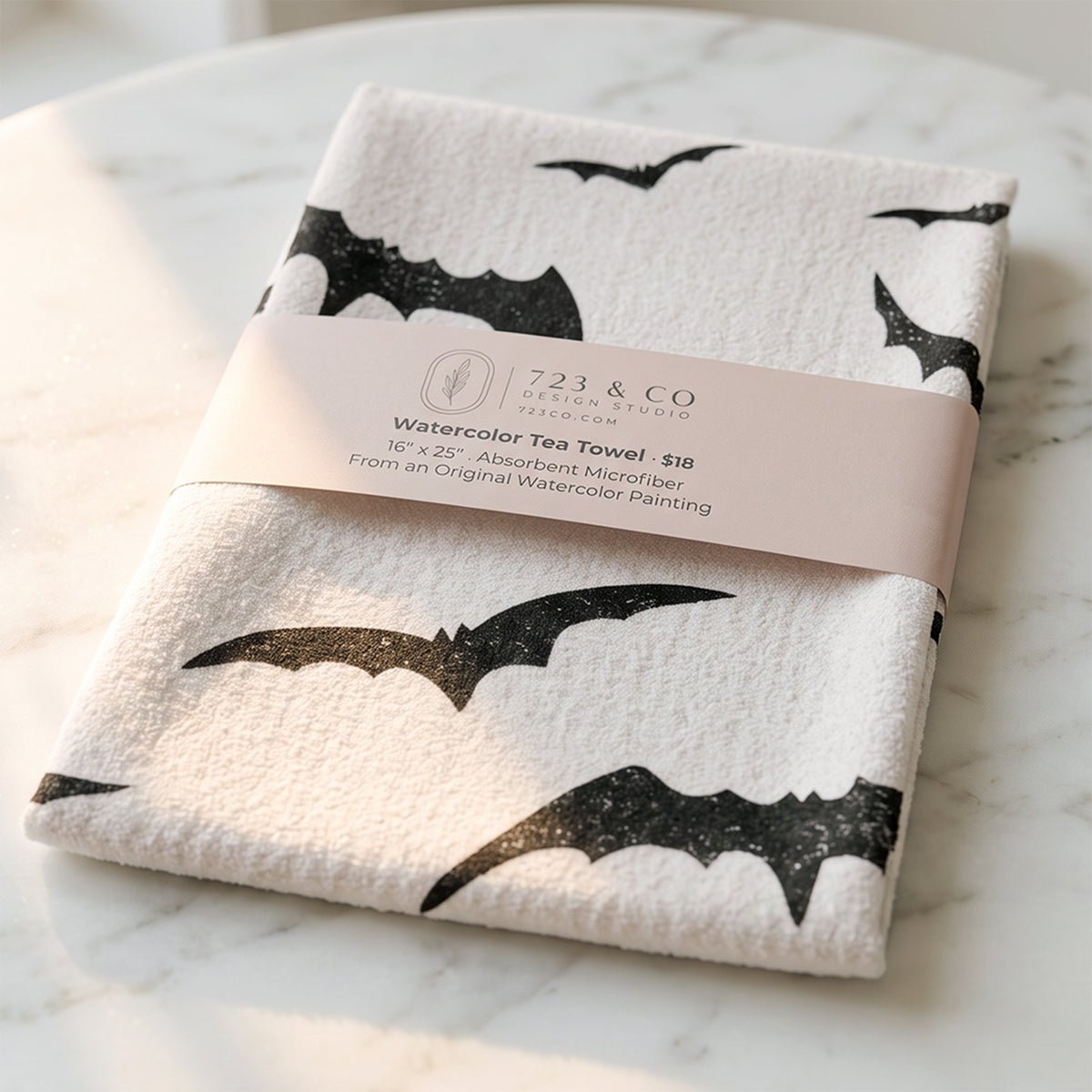 Bat Bash Halloween tea towel folded with 723 & Co. Design Studio belly band packaging, spooky kitchen linen